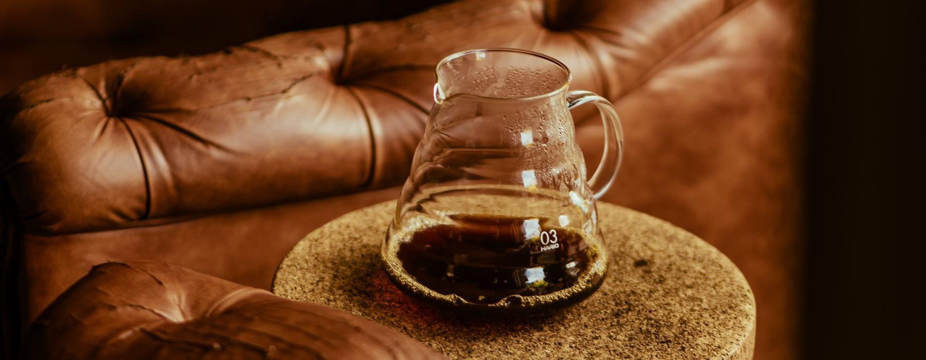a glass of coffee on a table next to leather chairs